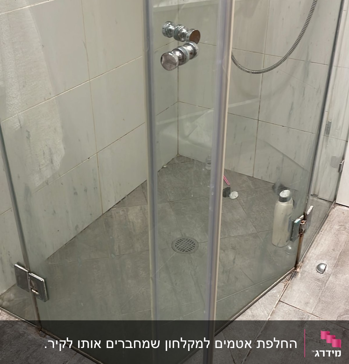 מקלחון זכוכית עם בקבוקי שמפו ומגבת לבנה